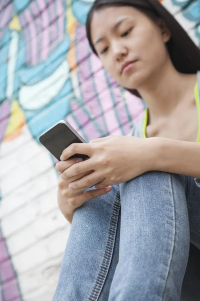 Kobieta patrząc w dół i SMS-y na jej telefon — Zdjęcie stockowe