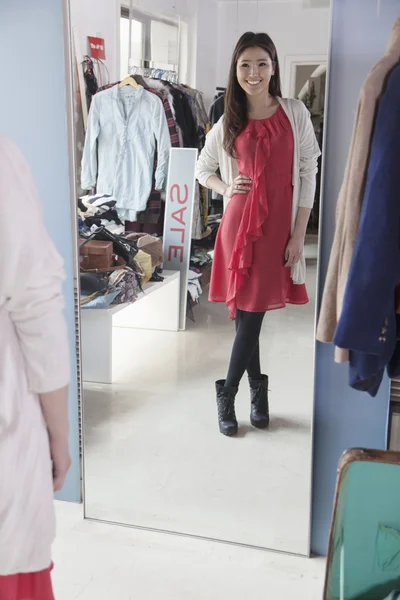 Frau sieht sich im Modegeschäft im Spiegel an — Stockfoto