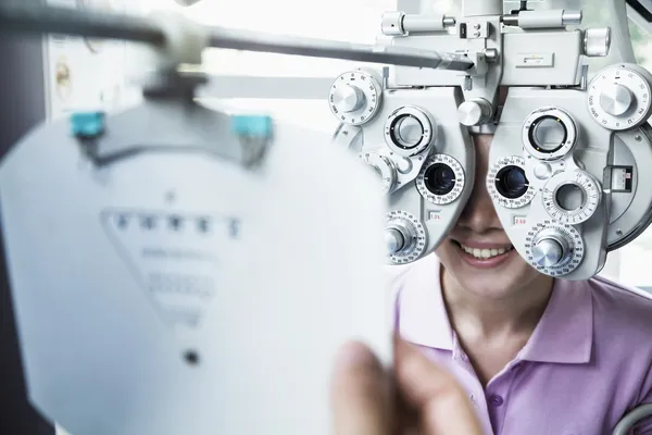 Optometrist doing an eye exam on young woman Stock Photo