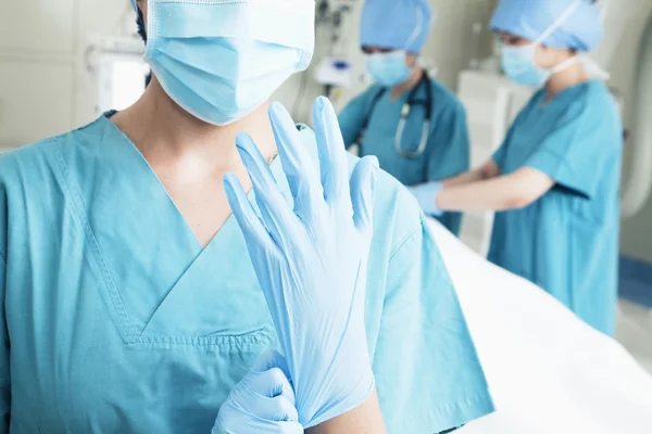 Surgeon putting on gloves in the operating room Stock Photo