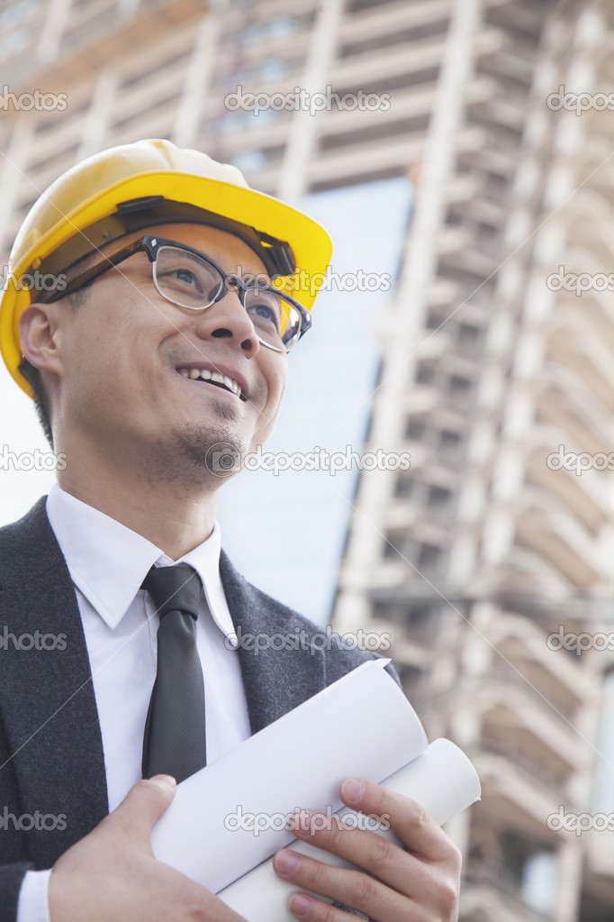 Architect on site carrying blueprints