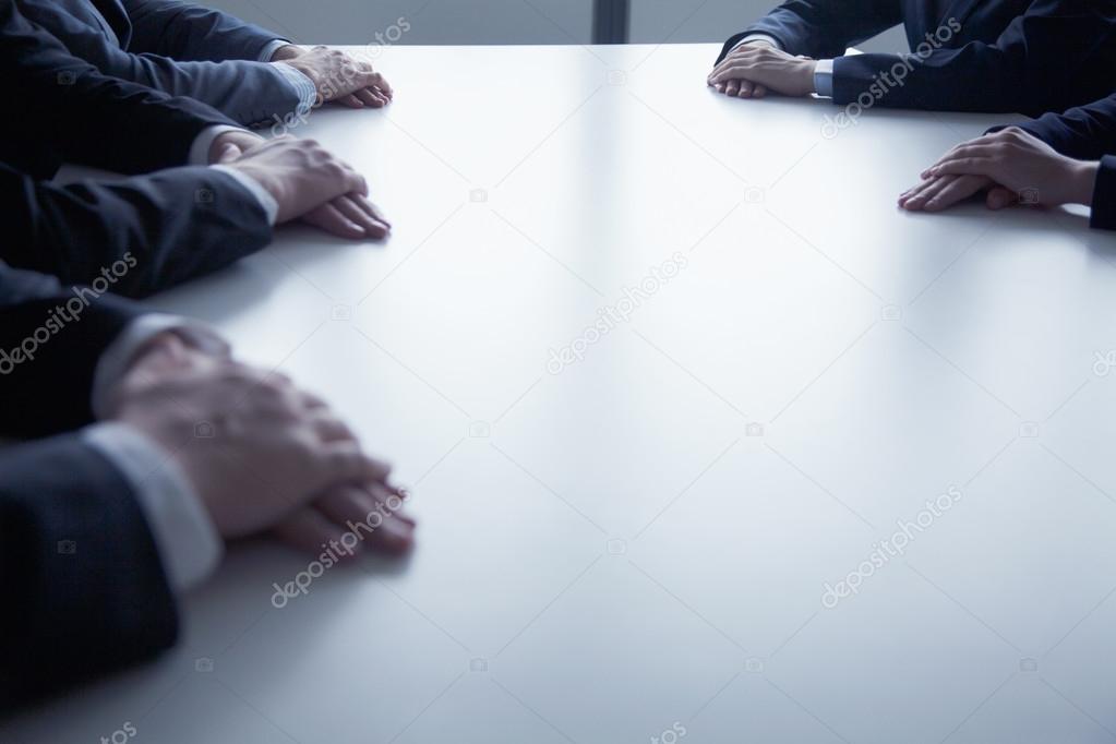 Folded hands of business people at the table
