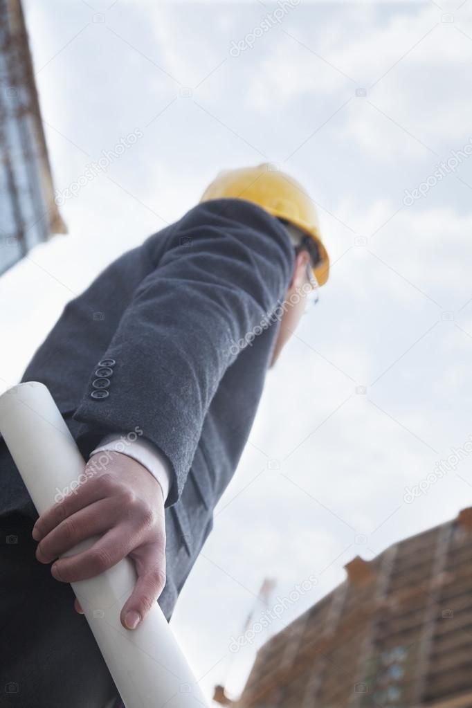 Architect holding blue print and looking up