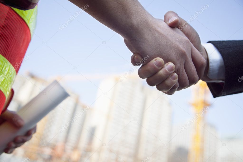 Architect and building contractor shaking hands