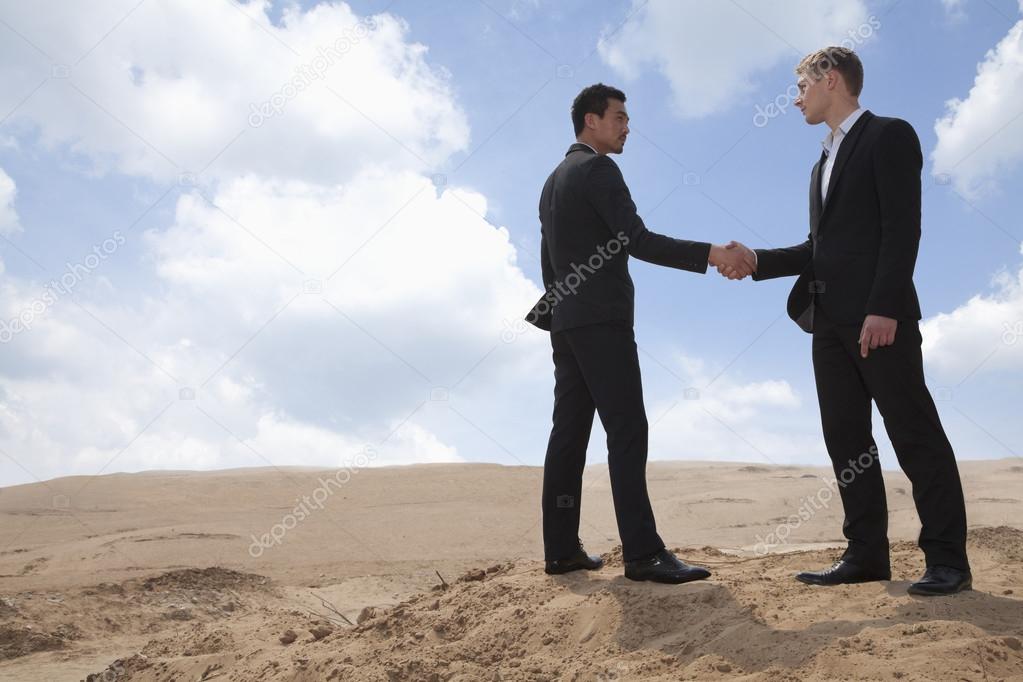 Businessmen shaking hands in the desert