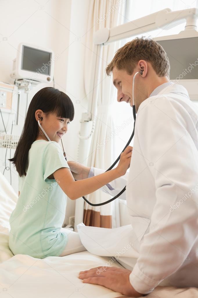 Girl patient checking the doctors heart beat