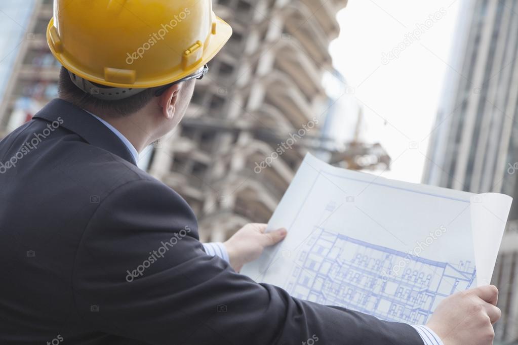 Architect on site looking at blueprints