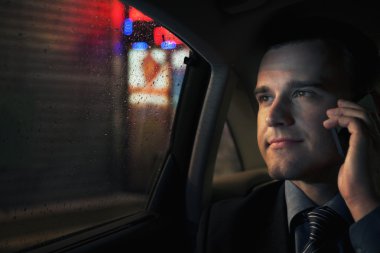 bir arabanın arka koltuğunda telefonda işadamı