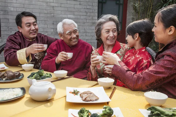 Famiglia con tazze alzate brindare su un pasto cinese — Foto Stock