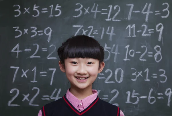 Schoolgirl in front of blackboard with math equations — Stock Photo, Image