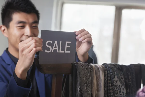 Winkelbediende zetten up "" te koop"" teken op mode — Stockfoto