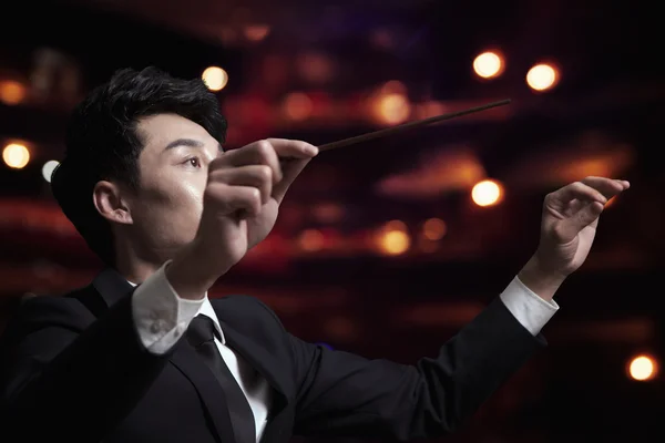 Conductor with baton raised at a performance — Stock Photo, Image