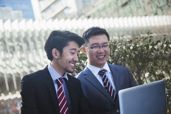 Zakenlieden kijken laptop samen buitenshuis — Stockfoto