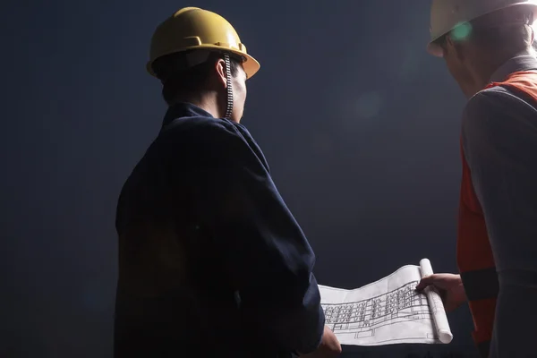 Engineers looking down at a blueprint at dusk — Stock Photo, Image