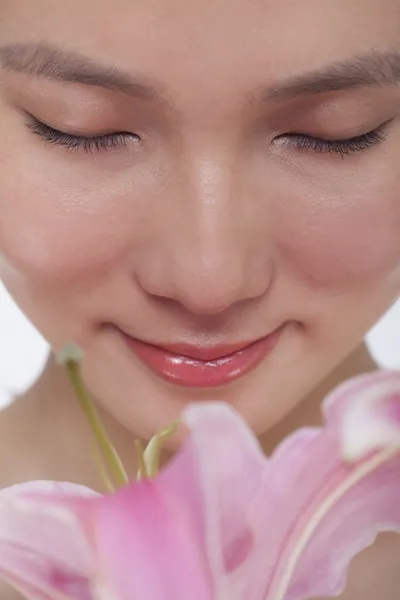 Woman smelling a large pink flower — Stock Photo, Image