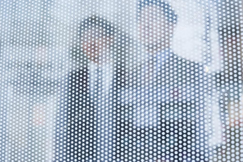 Businessmen behind a glass wall looking out