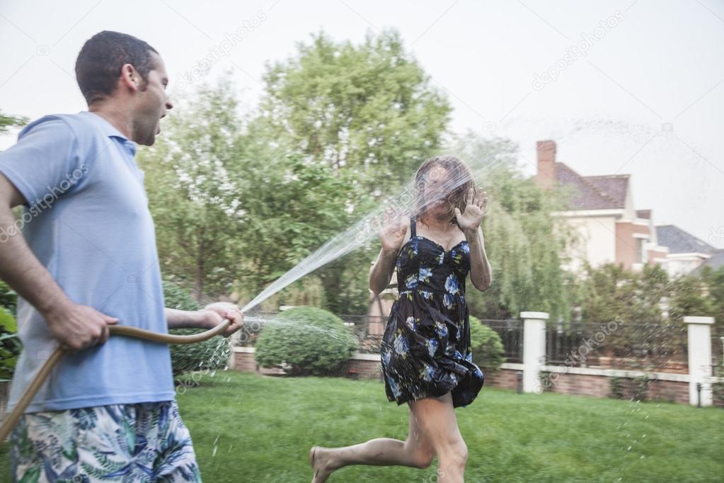 Couple playing with a garden hose