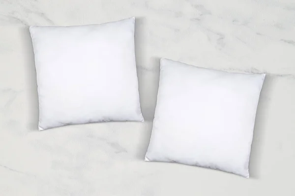 Two lucky white throw pillows napping on a luxurious white marble background.