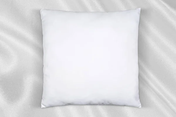 Square white throw pillow resting elegantly on a flowing silk background.