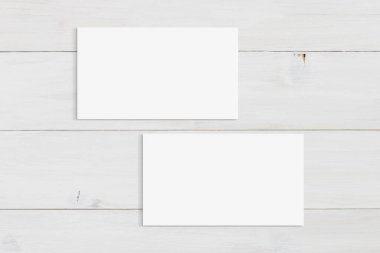 Modern beyaz ahşap arka planda duran iki kartvizit. Tasarımlarınızı kartlara eklemek için kırpma yolu içerir.