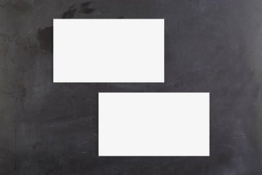 Tebeşir tahtasında duran iki beyaz kartvizit. Tasarımlarınızı kartlara eklemek için kırpma yolu içerir.