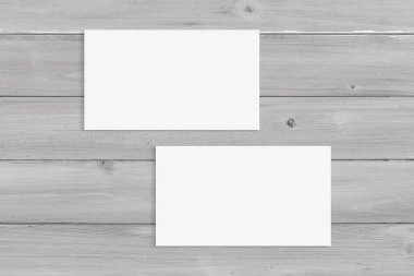 Top view of two blank white business cards atop a modern gray wood background. Includes clipping path to make it easy to add your designs to the cards.