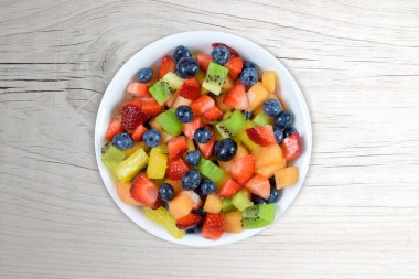 Modern beyaz ahşap arka planda rengarenk taze meyve salatası manzarası..