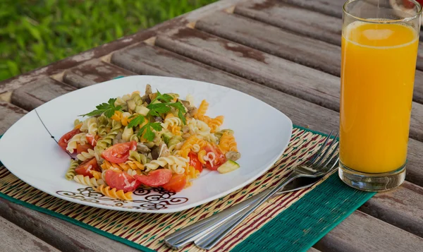 Pasta con verduras y un vaso de jugo de naranja fresco — Foto de Stock