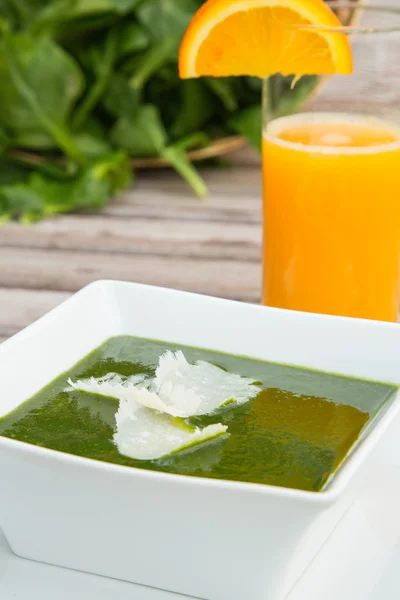 Суп со шпинатом и стакан свежего апельсинового сока — стоковое фото