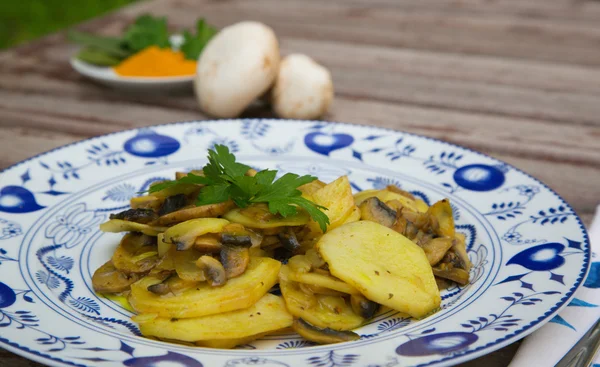 Gebakken aardappelen met paddestoelen en peterselie op het witte blauwe plat — Stockfoto