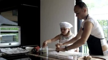 Anne ve kızı evde pizza için hamur yapıyorlar.