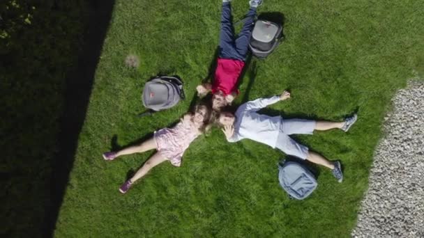 三个孩子躺在自家院子里的草地上的空中景象 — 图库视频影像