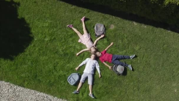 三个孩子躺在自家院子里的草地上的空中景象 — 图库视频影像
