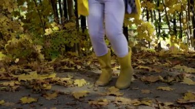 Sonbahar yapraklarıyla parkta dans eden küçük kız.