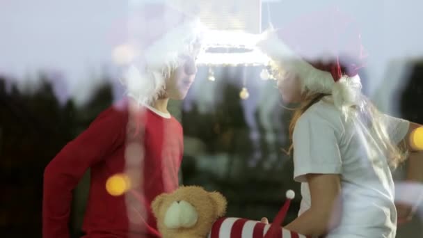 Two Kids Wearing Christmas Hats Sitting Giving Gift Boxes Each — 图库视频影像