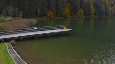 Erkek ve kız kardeşler dağlardaki gölde tahta iskelede.