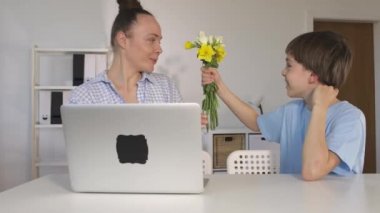 12 yaşında bir çocuk annesine bir demet çiçek sunar.