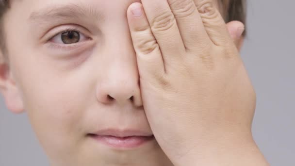 Caucásico chico de 9 años cierra el ojo con una palma. — Vídeos de Stock