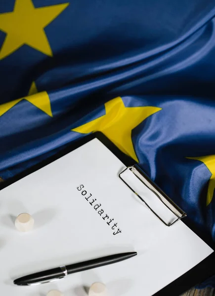 Word SOLIDARITY is written on the paper. EU Flag. Closeup — Stock Fotó