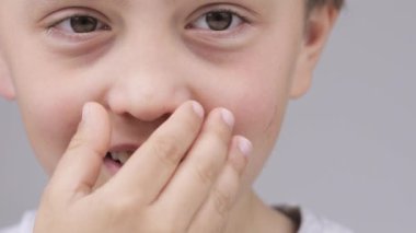 Caucasian boy of 9 years expresses unsatisfaction with a smell in the room.