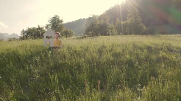 Boy houdt het huis en de windturbine. — Stockvideo