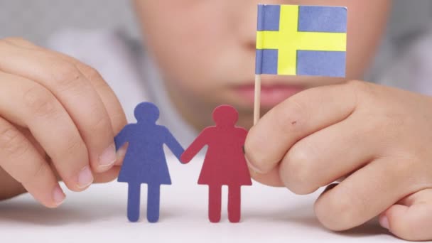 Mujeres de papel en manos de un niño con bandera sueca. — Vídeos de Stock