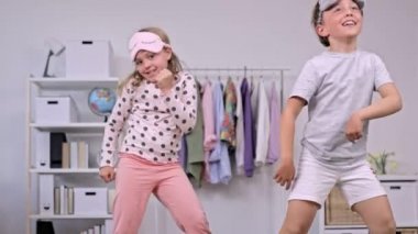 Pijama giymiş kız ve erkek kardeş birlikte dans ediyorlar. Ağır çekim. Yüksek kalite 4k görüntü