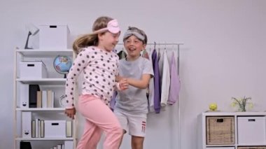 Pijama giymiş kız ve erkek kardeş birlikte dans ediyorlar. Ağır çekim. Yüksek kalite 4k görüntü