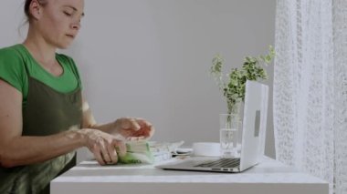 38-40 yaşları arasında beyaz bir kadın parayı elinde tutarken bazı notlar alıyor. Yavaş çekim