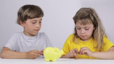 Erkek ve kız kardeşi domuz kumbarasına bozuk para koyuyorlar. Yavaş çekim