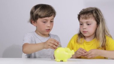 Erkek ve kız kardeşi domuz kumbarasına bozuk para koyuyorlar. Yavaş çekim