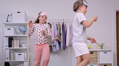 Pijama giymiş kız ve erkek kardeş birlikte dans ediyorlar. Ağır çekim. Yüksek kalite 4k görüntü