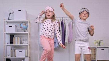 Pijama giymiş kız ve erkek kardeş birlikte dans ediyorlar. Ağır çekim. Yüksek kalite 4k görüntü