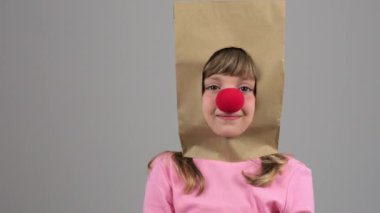 Funny Caucasian girl of 7 years with red nose makes some music sounds. High quality 4k footage